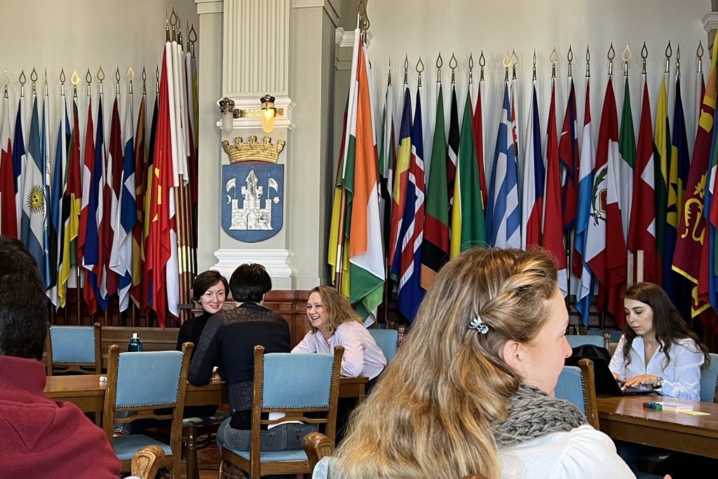 Participants sitting in a room full of different flags. 