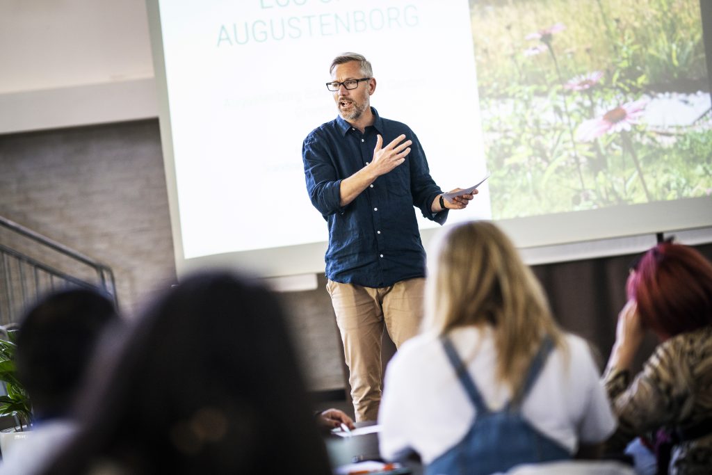 Björn Wickenberg standing in front of a powerpoint presentation talking to the participants 