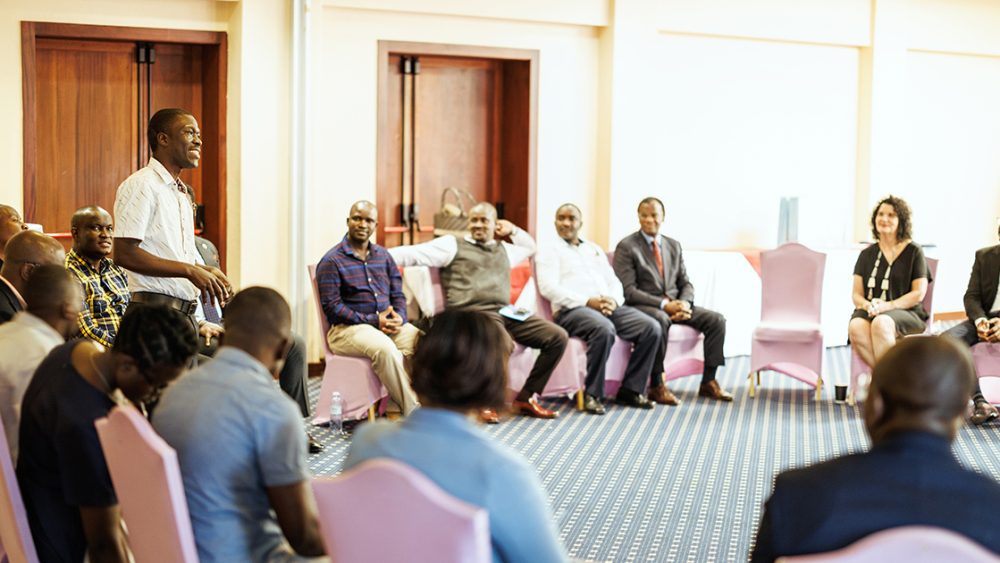 Participants in the programme sitting in a circle listening to a man talking.